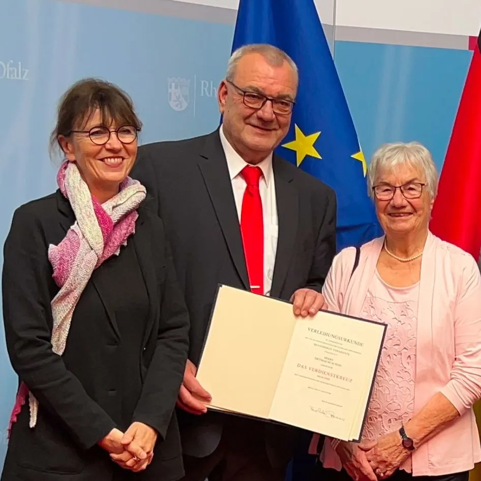 Dietmar Muscheid eingerahmt von seiner Frau und seiner Mutter vor der Europaflagge.